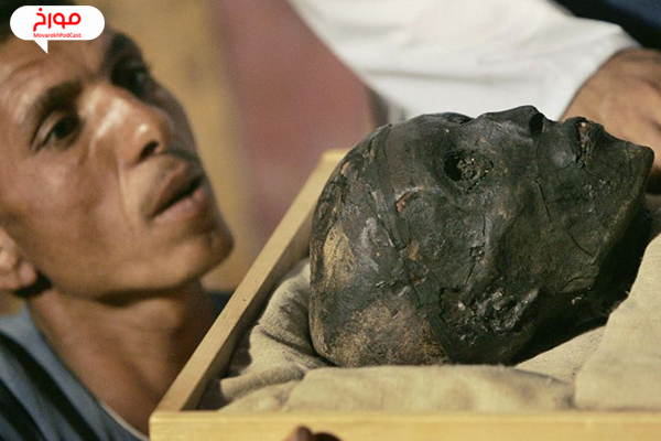 یک کارمند باستان شناسی در سال 2007 در حالی که مومیایی به یک کیس تحت کنترل آب و هوا منتقل می شود، به چهره پادشاه توتانخامن نگاه می کند.